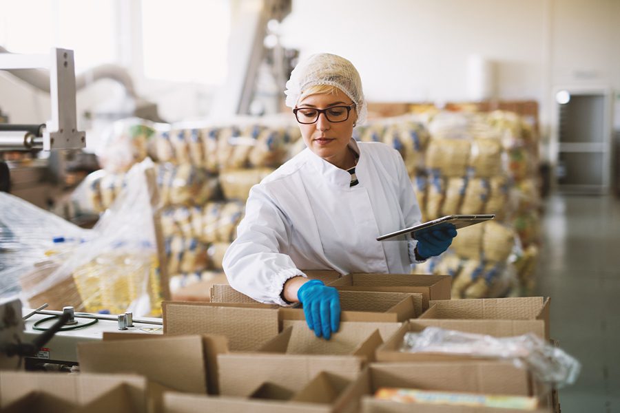 Food Distributors Insurance - Employee in Sterile Clothes Checking Food Packages Ready to be Delivered